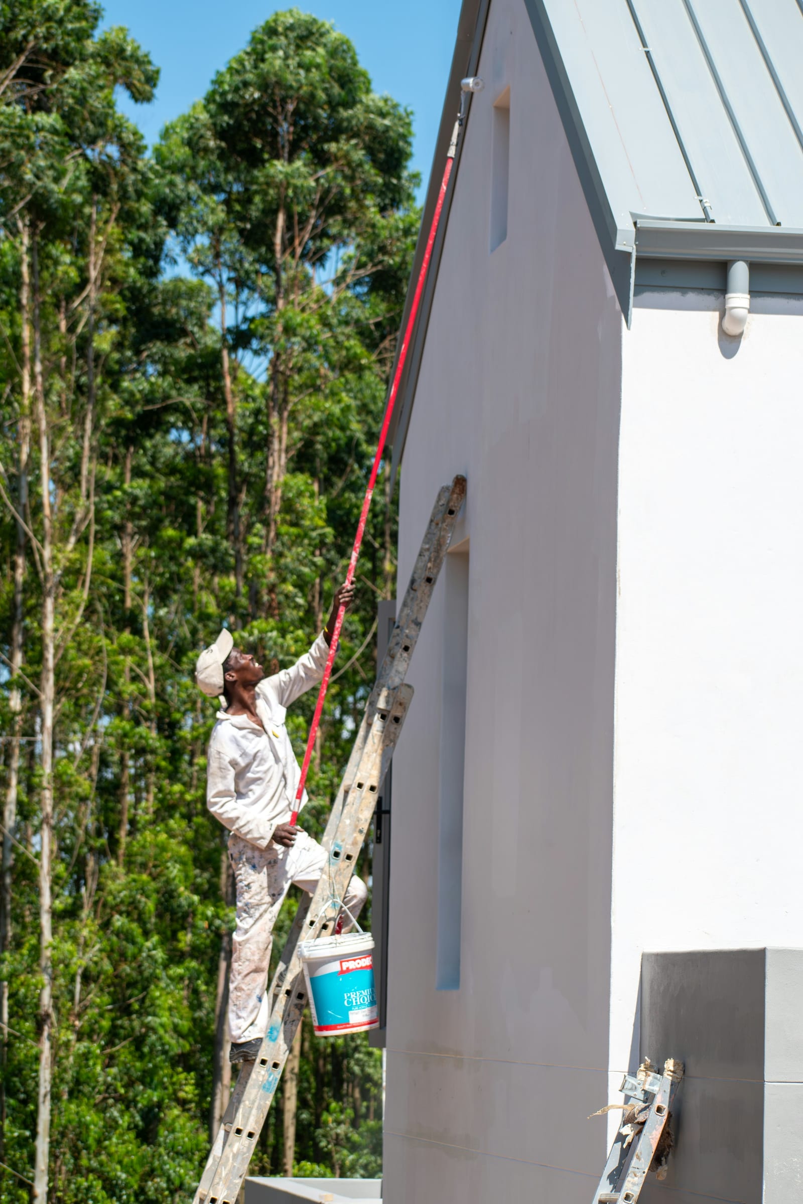 A painter applying exterior paint to a house in North Texas.