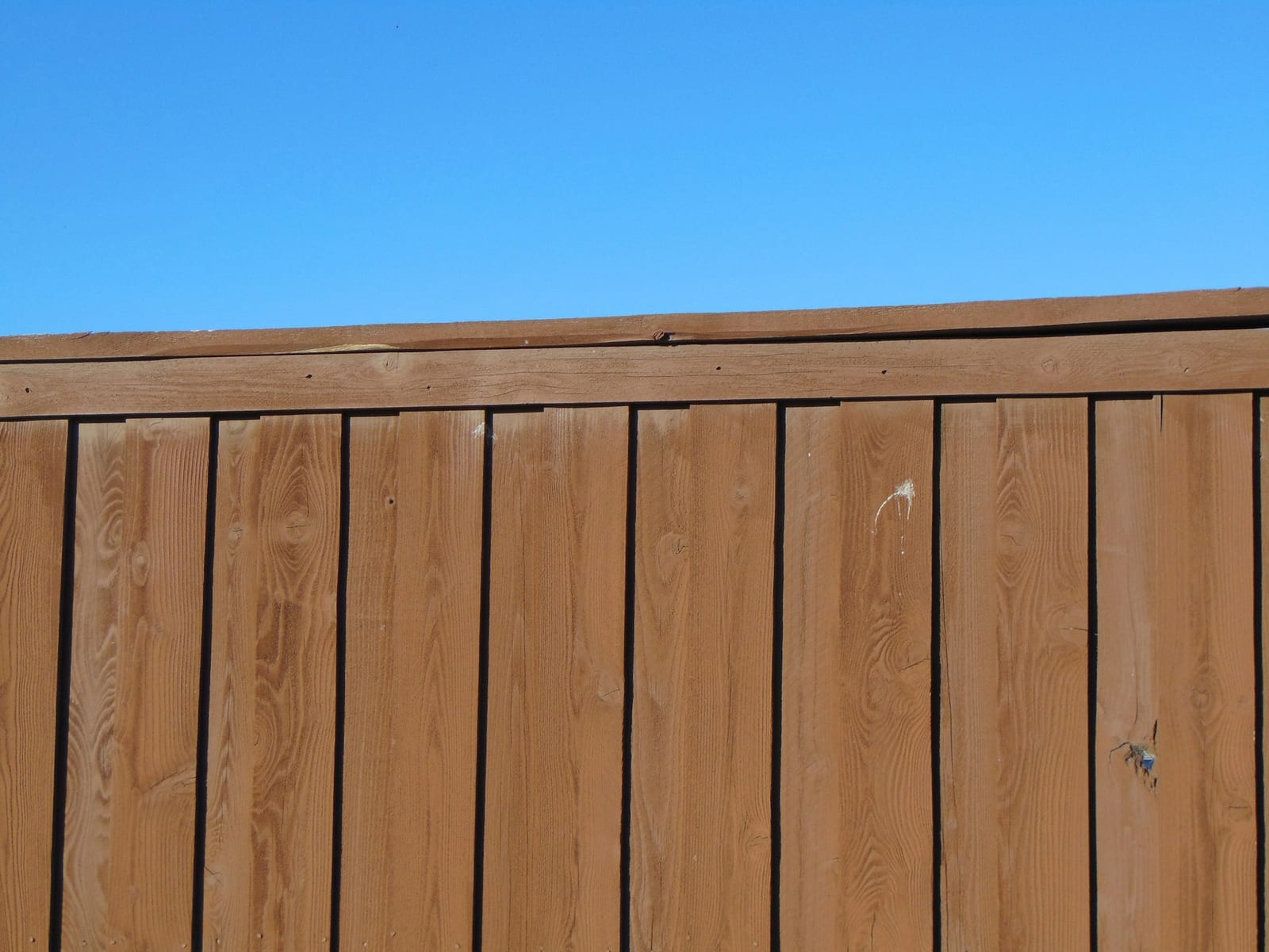 A freshly painted and stained wood fence in Garland, TX.